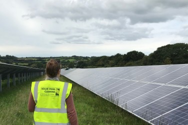 A woman in a yellow vest standing in front of solar panels